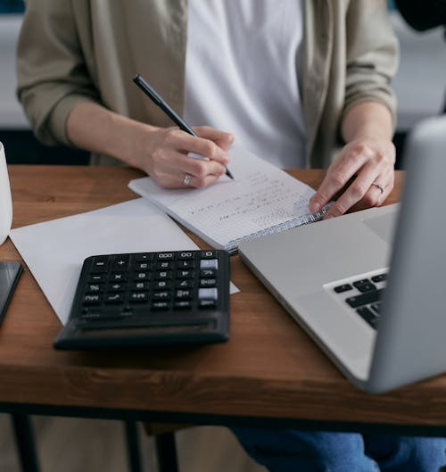 Bookkeeping documents, calculator, and notebook on a business desk.
